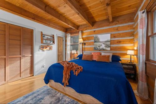 a bedroom with a blue bed and wooden walls at The Mountain Forager Cabin, Bryson City NC in Bryson City