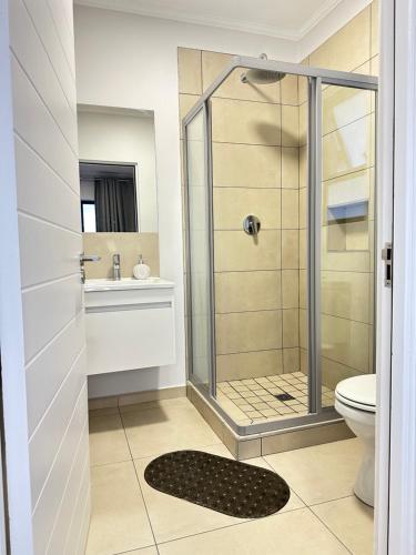 a bathroom with a shower and a toilet and a sink at Elusive Haven in Nelspruit