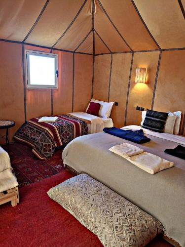 a room with two beds in a tent at Tasnim Désert Camp & Activités in Merzouga