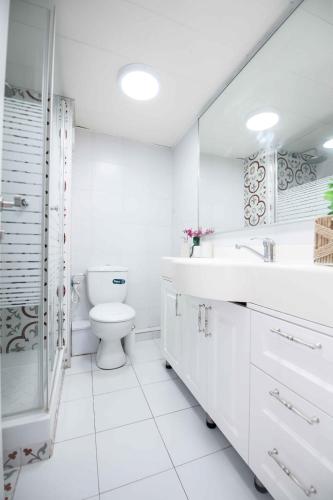 a white bathroom with a toilet and a sink at מול הים בקיסריה in Caesarea