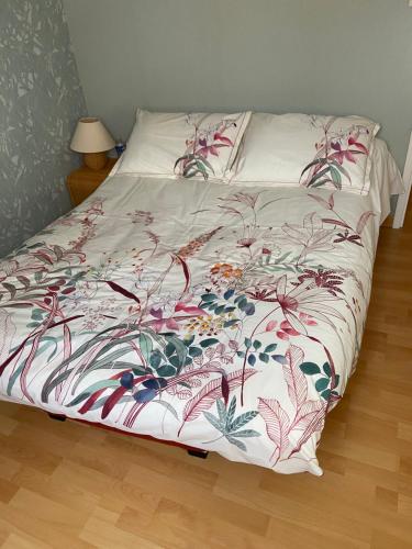 ein Bett mit einer Blumendecke darauf in der Unterkunft Le Hameau du moulin a vent in Saint-Avertin