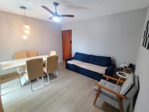 ein Wohnzimmer mit einem blauen Sofa und einem Tisch und Stühlen in der Unterkunft Apartamento Térreo 2 Quartos Com Clube Privativo - Condomínio Marina Clube in Cabo Frio