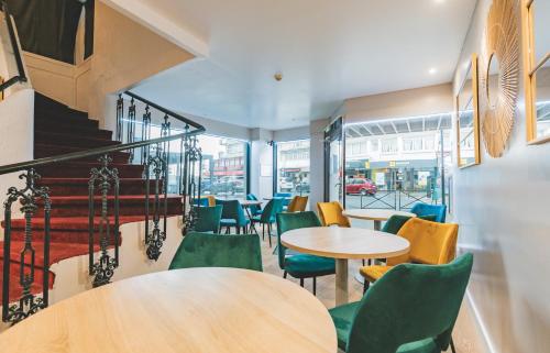 a restaurant with tables and chairs and a staircase at Le Faidherbe Hotel Coeur de ville in Boulogne-sur-Mer