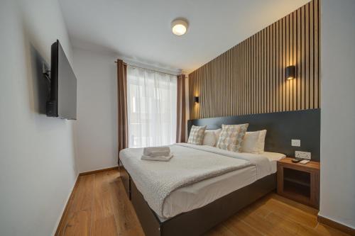 a bedroom with a large bed and a television at Tritoni Alta suites in Il-Gżira