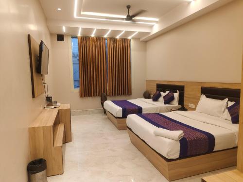 ein Hotelzimmer mit zwei Betten und einem Fernseher in der Unterkunft Family Rooms Only By Provide The URO Group - Main Bazar Paharganj in Neu-Delhi