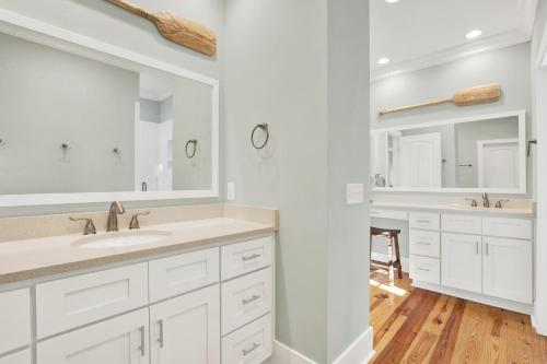 Un baño blanco con lavabo y espejo. en Cherokee Rose, en Tybee Island