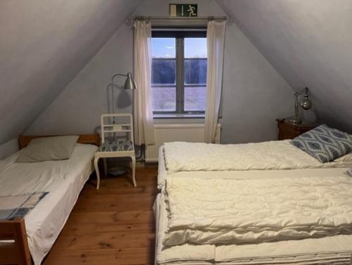 ein Schlafzimmer im Dachgeschoss mit zwei Betten und einem Fenster in der Unterkunft Eternellgården, Stenshuvudsvägen , Kivik in Kivik