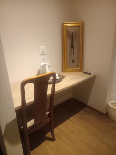 einen Schreibtisch mit einem Stuhl und einem Spiegel in einem Zimmer in der Unterkunft Good Times Cafe in Teyateyaneng