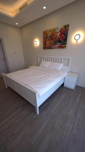 a bedroom with a large white bed with a painting on the wall at شاليه العائله Shaleeh 285 in Al Khīrān