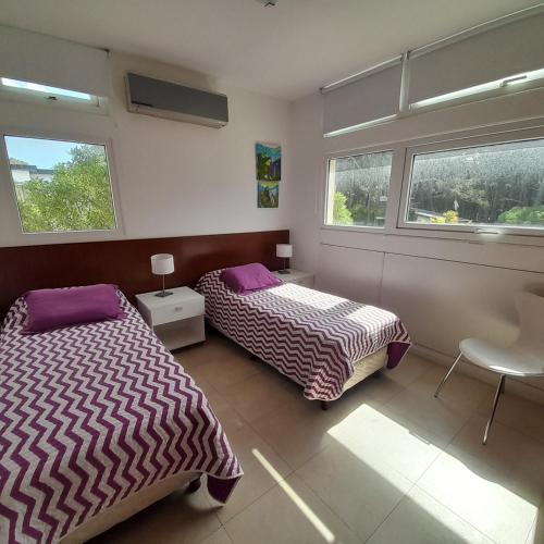 two beds in a room with two windows at Manzana 1 in Mar de las Pampas