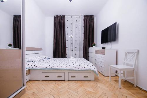 ein Schlafzimmer mit einem Bett, einer Kommode und einem Fernseher in der Unterkunft Cozy central apartament in Craiova