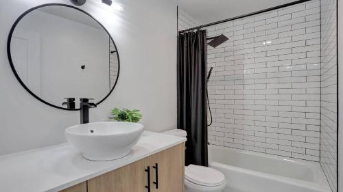 ein Badezimmer mit Waschbecken, Spiegel und Badewanne in der Unterkunft Karmen's Lake Cottage A1 in SeaTac