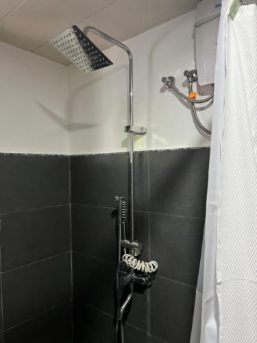 eine Dusche in einem Badezimmer mit einer schwarzen Fliesenwand in der Unterkunft Northern Belle guesthouse in San Fernando