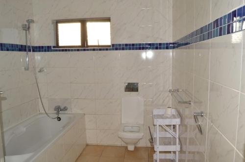 a bathroom with a toilet and a tub and a sink at Woodmead Meadows in Harare