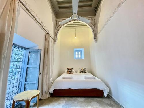 Suite John Pawson Dar Kiki Medina, Tunis في تونس: غرفة نوم بها سرير ونافذة كبيرة