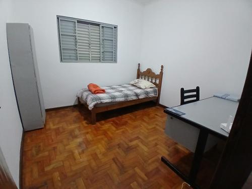 a room with a bed and a desk and a table at Home office solteiro aconchegante no Centro de Poços de Caldas in Poços de Caldas