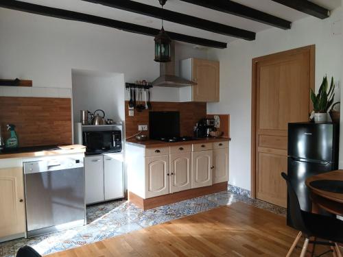 Una cocina con electrodomésticos blancos y un refrigerador negro. en Studio indépendant T1, entre Nantes et Rennes, en Conquereuil