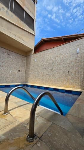 a swimming pool with a metal railing in front of a building at Casa com Piscina Peró in Cabo Frio