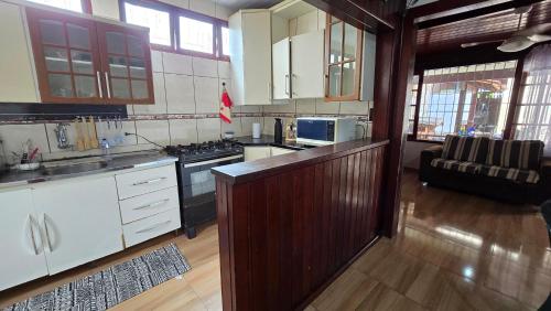 a kitchen with white cabinets and a stove top oven at Casa com Piscina Peró in Cabo Frio