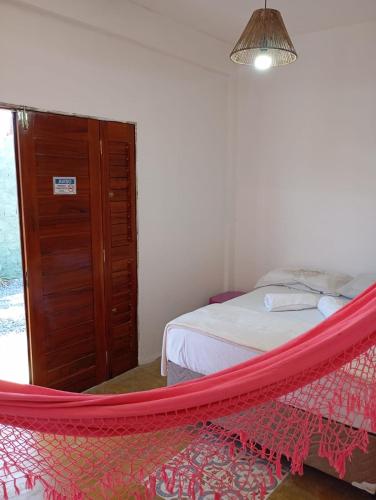 a red hammock in a bedroom with a bed at Pousada Paraíso das Dunas in Barroquinha