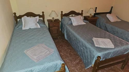 two twin beds in a room with two lamps at Hosteria LA VIEJA CARRETA in Purmamarca