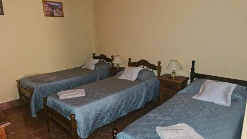 a room with two beds and two tables with lamps at Hosteria LA VIEJA CARRETA in Purmamarca