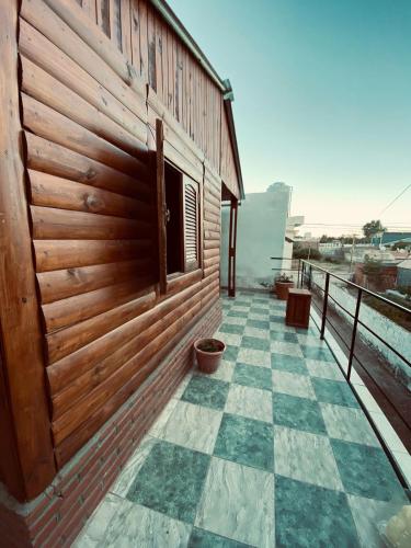 a wooden building with a tiled floor next to a wall at Cabañas El Zonda in Tinogasta