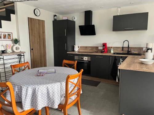 una cucina con un tavolo con sedie e una cucina con mobili neri di Ker Zélia a Cruguel
