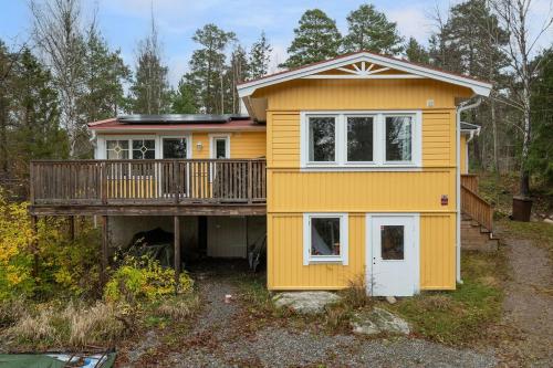 a yellow house with a porch and a deck at Modern family home next to Mälaren in Mariefred in Mariefred