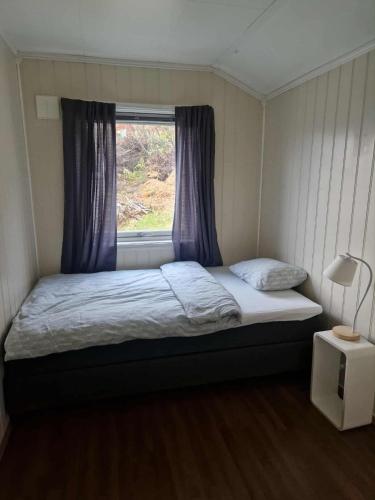 a small bedroom with a bed with a window at House with terrace and a big garden in centrum of Lyngseidet in Lyngseidet