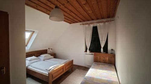 a bedroom with a bed and a wooden ceiling at Kolonics Pincészet Vendégház Somló in Somlóvásárhely