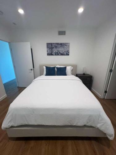 ein Schlafzimmer mit einem großen weißen Bett mit blauen Kissen in der Unterkunft Lavender-modern 2 bed apartment with water view in San Diego
