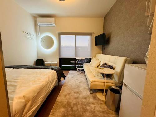 ein Schlafzimmer mit einem Bett, einer Couch und einem Tisch in der Unterkunft LuxurySweet 博多駅南52 in Fukuoka