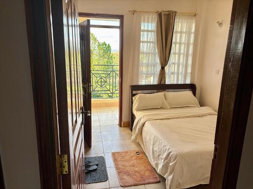1 dormitorio con 1 cama y puerta a un balcón en Loresho Luxe stay, en Nairobi