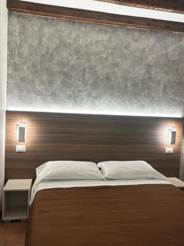 a bedroom with a large bed with a wooden headboard at Deattellis House accogliente mansarda in palazzo storico in Campobasso