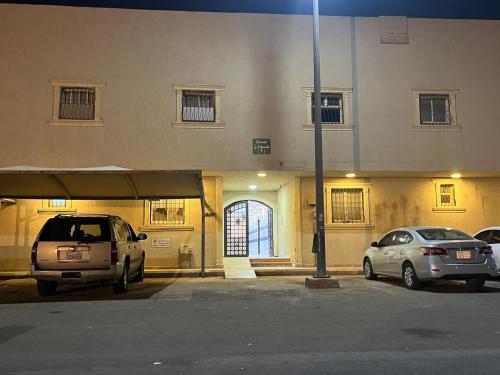 zwei Autos auf einem Parkplatz vor einem Gebäude geparkt in der Unterkunft شقة فاخرة غرفة ماستر مع صالة in Ar Rass