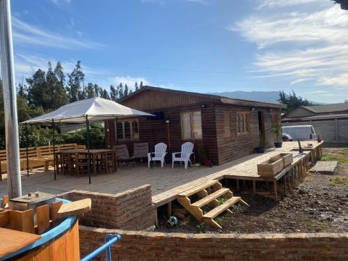 een houten terras met een tafel en een parasol bij Cabañas Venecia in El Monte