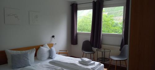 a bedroom with a bed and two chairs and a window at Weingut Fehres in Brauneberg