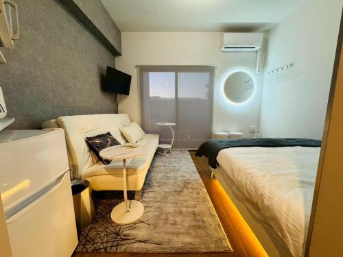 ein Schlafzimmer mit einem Bett, einer Couch und einem Tisch in der Unterkunft LuxurySweet 博多駅南53 in Fukuoka
