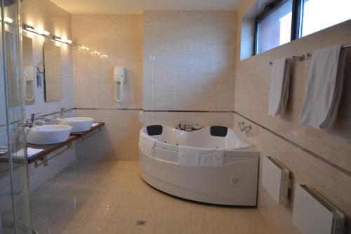 a bathroom with two sinks and a bath tub at Hotel Presidivm Palace in Lovech