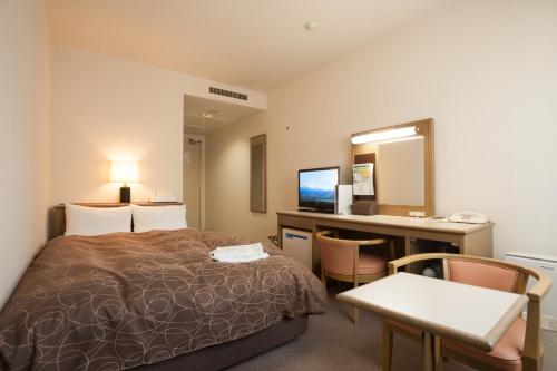 a hotel room with a bed and a desk at Hotel Yassa in Mihara