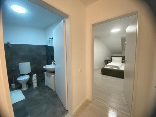 a bathroom with a toilet and a sink and a bed at Anacoco Deluxe Home in Herzogenrath