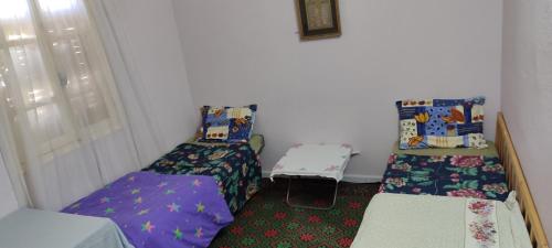 een kleine kamer met twee bedden en een raam bij Appartement Naim in Tozeur