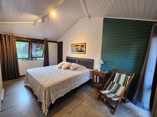a bedroom with a bed and a chair in it at Casa de praia com piscina e jacuzzi totalmente privativa in Imbituba