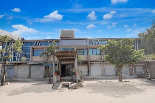 an apartment building with trees in front of it at Hotel O Vatva Railway Station Formerly Anmol Palace in Ahmedabad