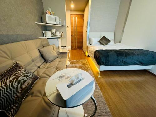 ein Wohnzimmer mit Sofa und Bett in der Unterkunft LuxurySweet 博多駅南62 in Fukuoka