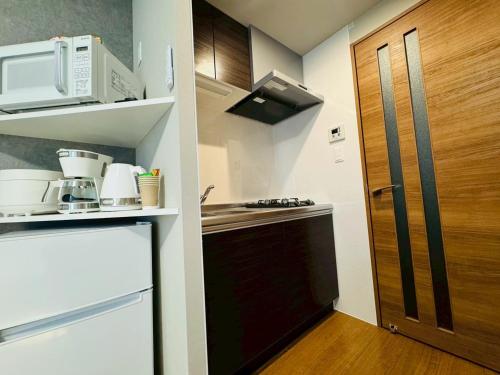 eine kleine Küche mit Spüle und Kühlschrank in der Unterkunft LuxurySweet 博多駅南62 in Fukuoka