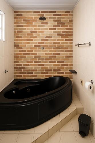 a black tub in a bathroom with a brick wall at Pousada 218 in Manaus