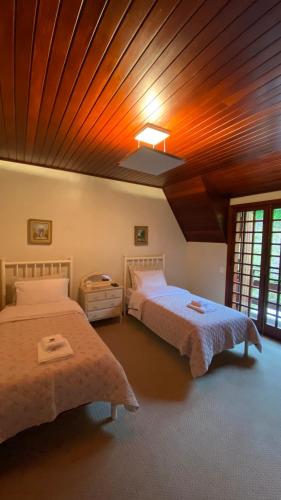a bedroom with two beds and a wooden ceiling at Villa Panorama in Campos do Jordão