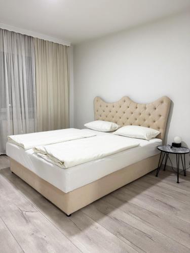 a white bedroom with a large bed and a window at Modern Lux Apartment in Brčko